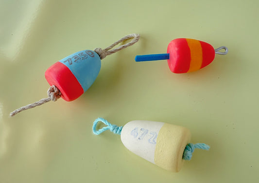 Three colorful buoy magnets on a light green background