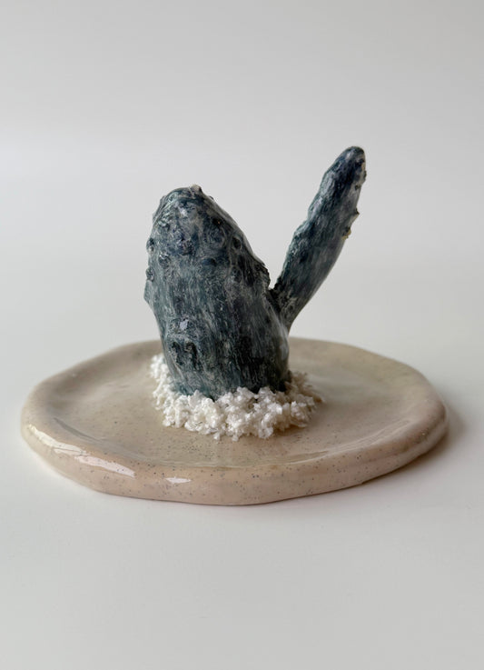 humpback whale breaching figurine on a beige base with a white background 