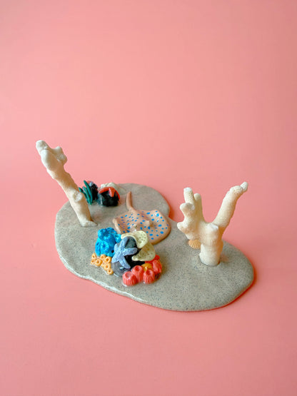 Decorative coral and fish figurines against a pink background