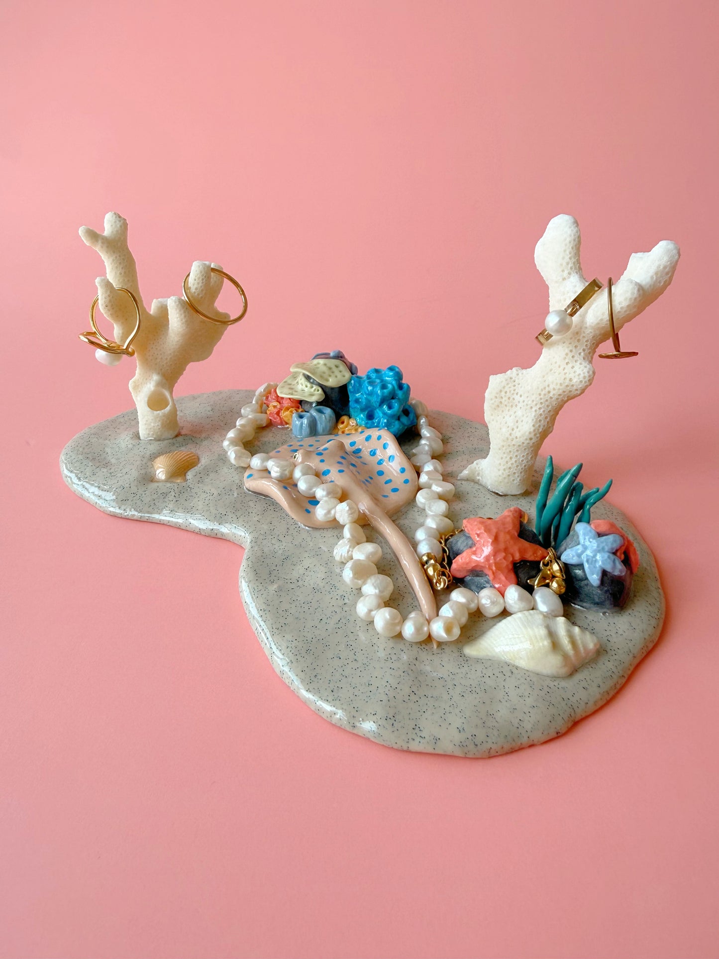 Jewelry holder with coral and starfish design on a pink background