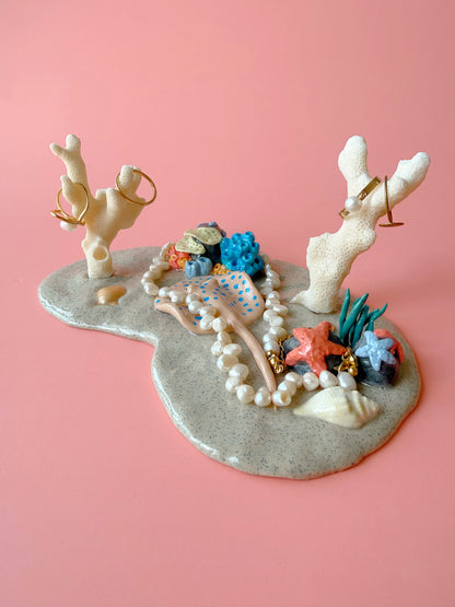 Jewelry holder with coral and starfish design on a pink background