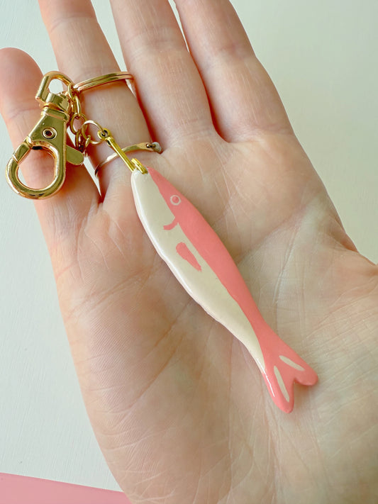 Pink fish-shaped keychain on a hand against a light background